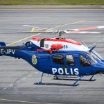 a police helicopter sitting on top of an airport runway