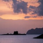 Silhouettes of People Standing on a Surfacing Submarine at Dusk