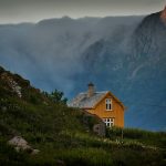 brown concrete house near mountains under white sky at daytime