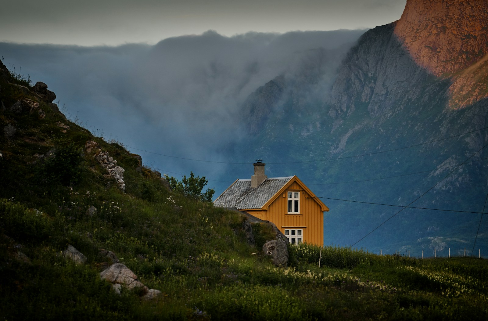 brown concrete house near mountains under white sky at daytime