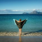 woman holding black towel standing on beach