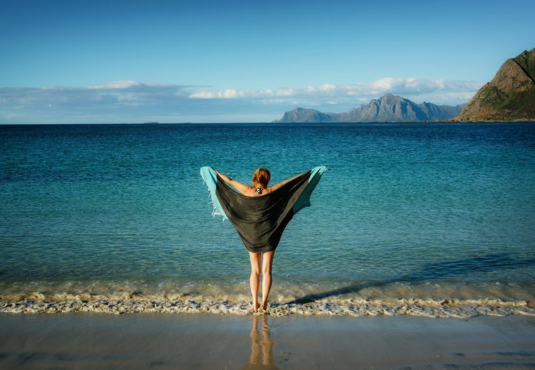 woman holding black towel standing on beach