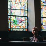 man sitting on pew chair