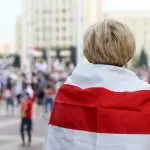 woman in white and red shirt standing on street during daytime