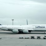 white and black Lufthansa airliner near vehicles