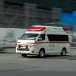 an ambulance driving down a street next to a building