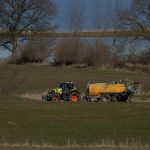 a tractor pulling a trailer behind it through a field