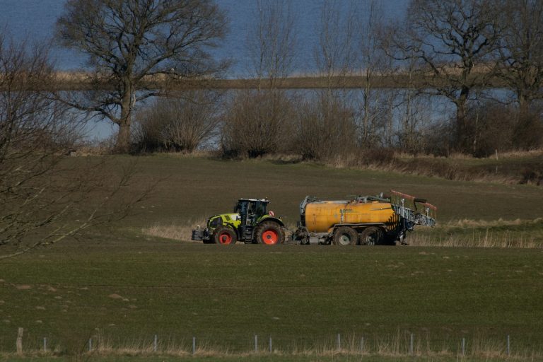 a tractor pulling a trailer behind it through a field