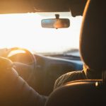 man driving car during golden hour