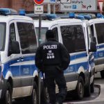 a police officer standing in front of a line of police vans