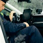 a police officer sitting in the driver's seat of a car