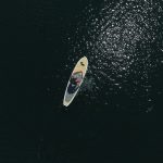 white and black surfboard on body of water