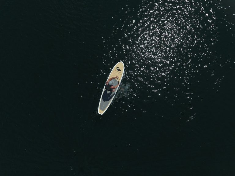 white and black surfboard on body of water