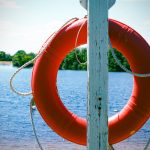 an orange life preserver hanging from a wooden pole