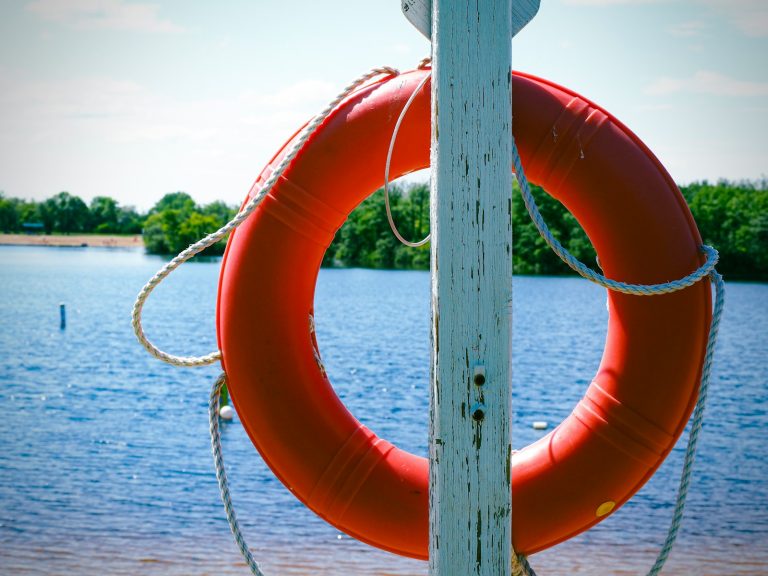 an orange life preserver hanging from a wooden pole