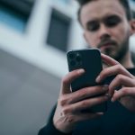 man wearing black sweater using smartphone