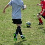 woman in white shirt and black shorts playing soccer