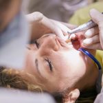 Woman's Teeth Being Clean By Dentist