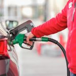 a person filling a car with gas at a gas station