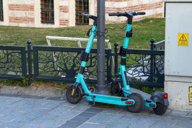 a blue scooter parked next to a black fence