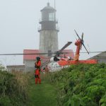 man in white shirt and orange pants standing near white lighthouse during daytime