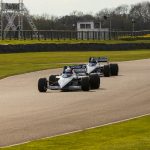 a couple of racing cars driving down a race track