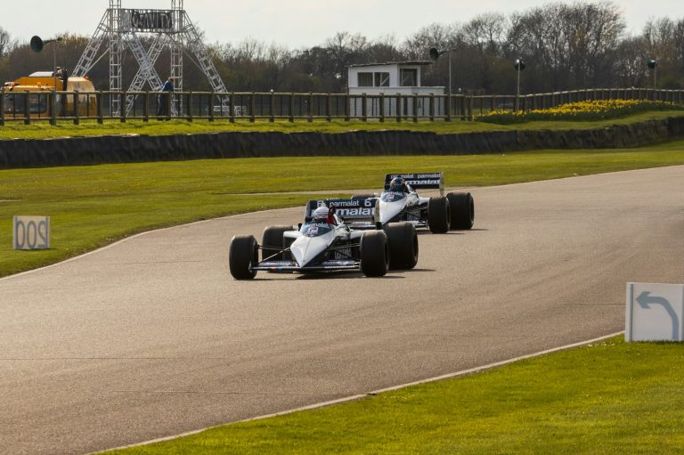 a couple of racing cars driving down a race track