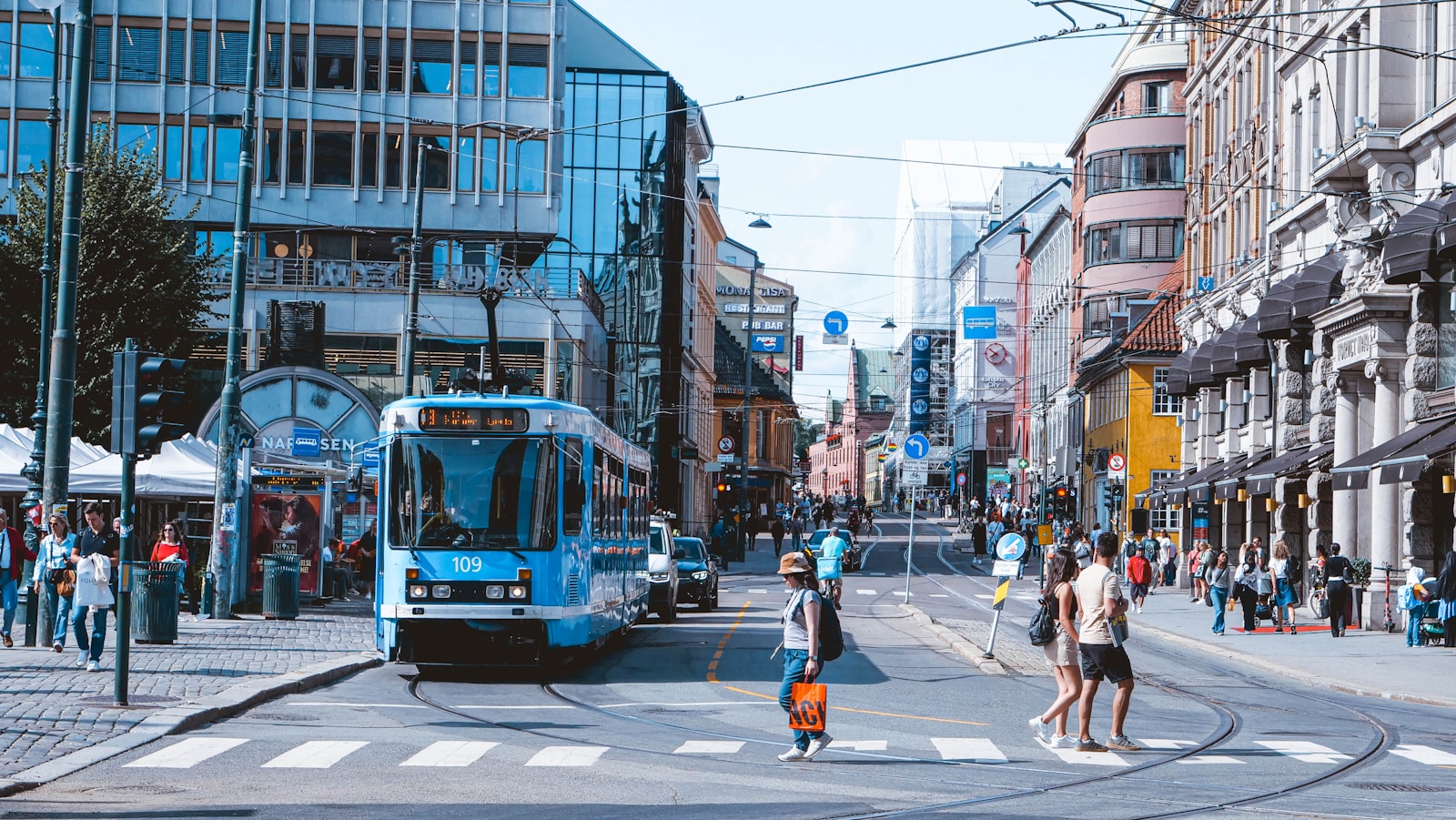 a blue bus driving down a street next to tall buildings