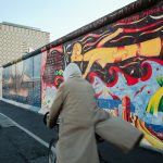 a woman walking down a street past a colorful wall