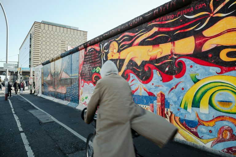 a woman walking down a street past a colorful wall