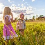 girl in pink and white dress standing on green grass field during daytime