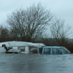 a van is in a flooded area with trees in the background