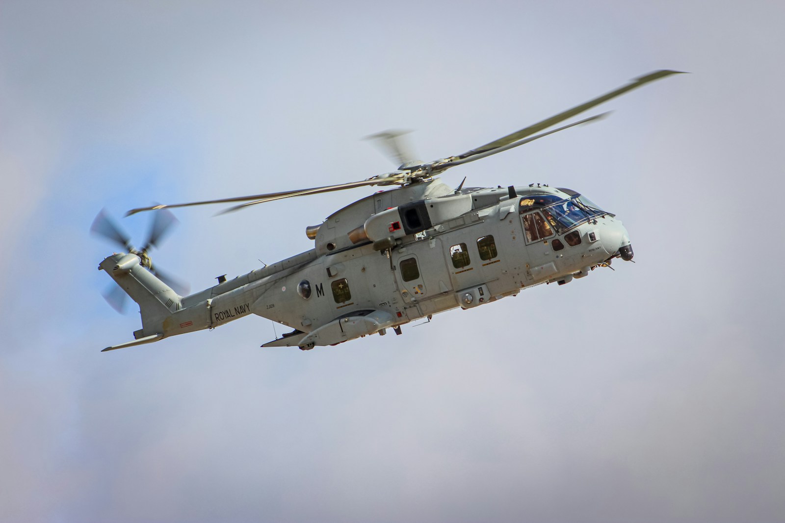 a military helicopter flying through a cloudy sky