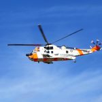 orange and white helicopter flying under blue sky during daytime