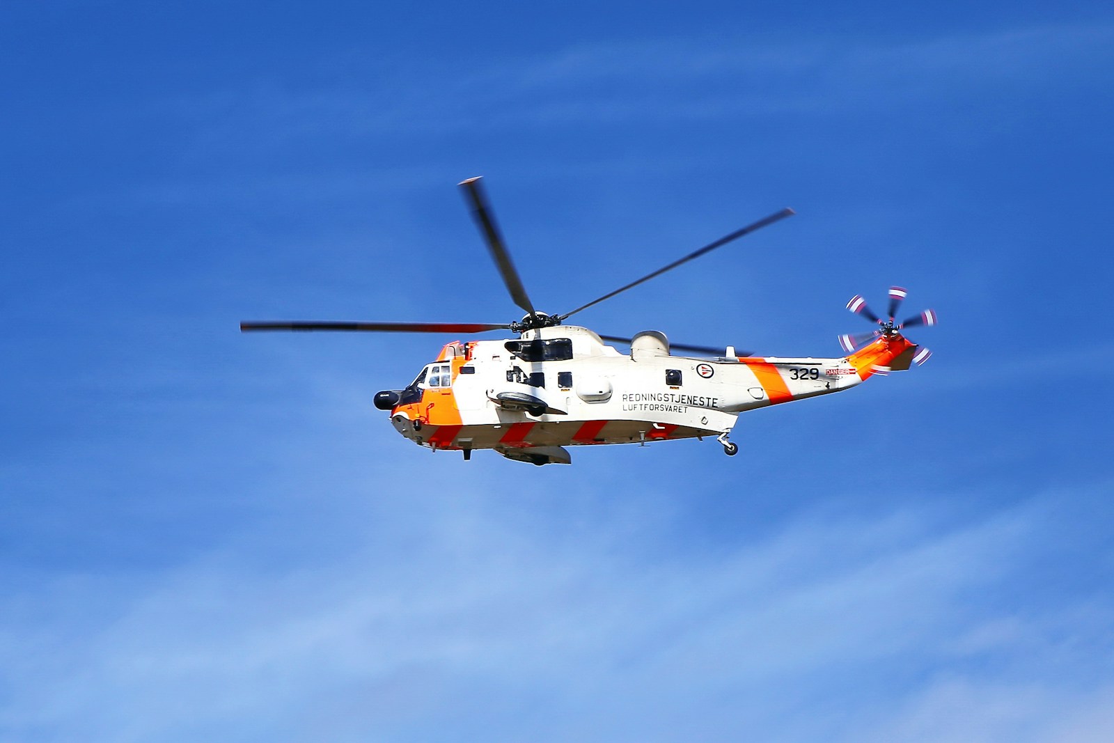 orange and white helicopter flying under blue sky during daytime