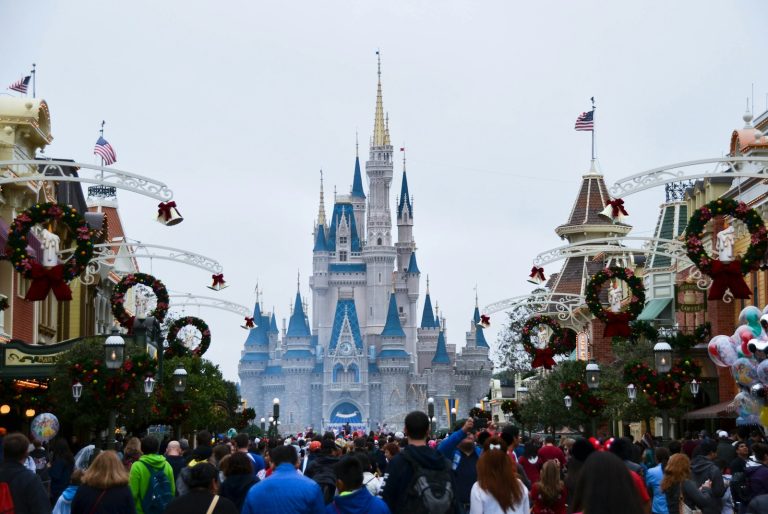 a crowd of people walking down a street in front of a castle