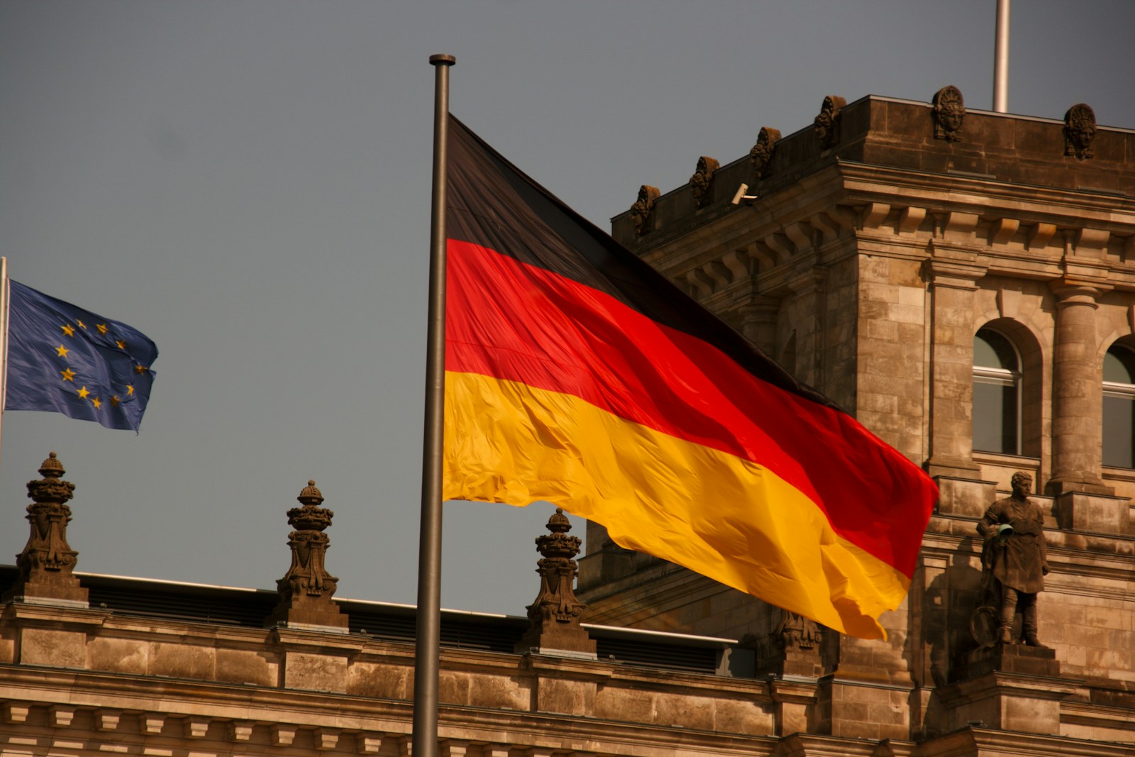 two flags flying next to each other in front of a building