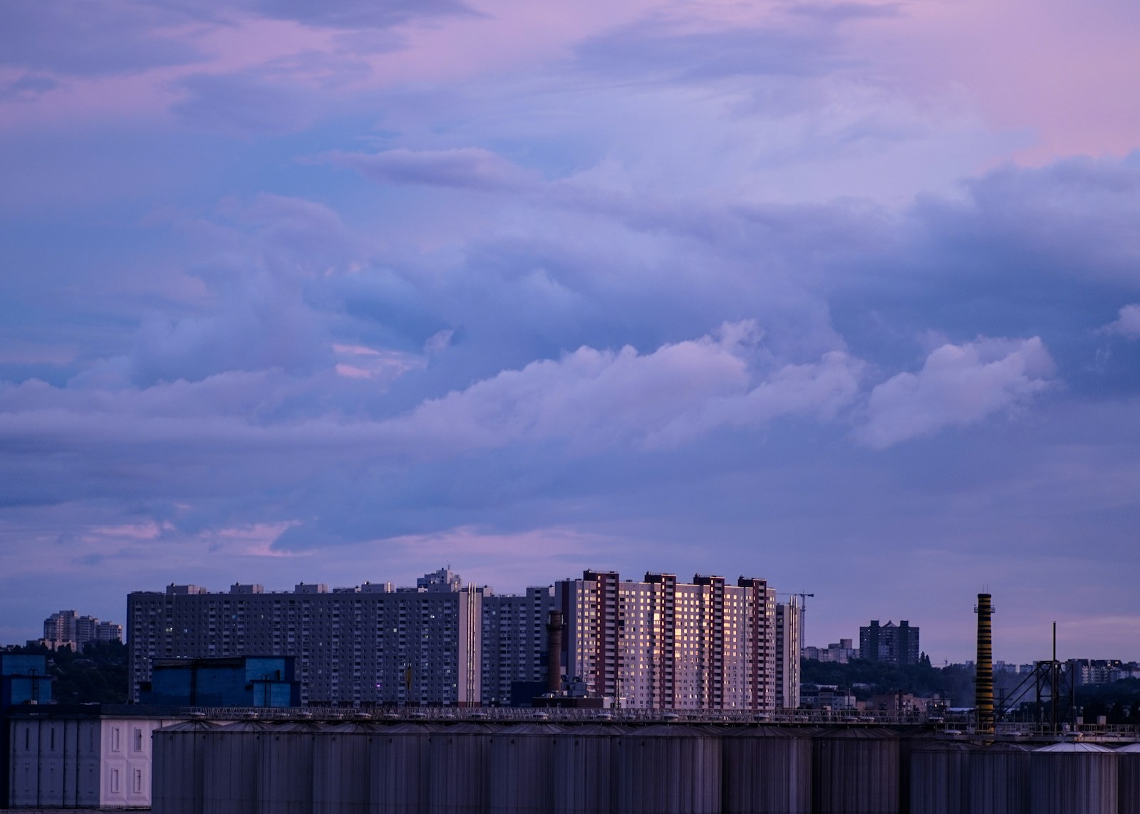 a plane flying over a city under a cloudy sky