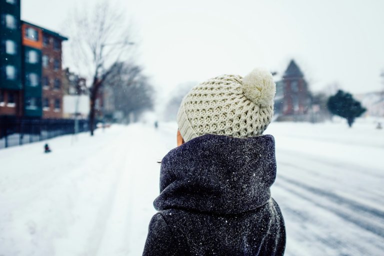 En kvinne står og ser når snøen faller ned fra himmelen