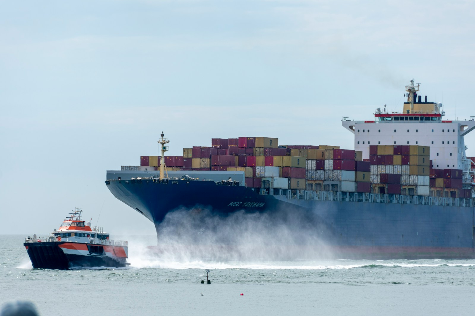 a large cargo ship in the ocean with a tug boat nearby