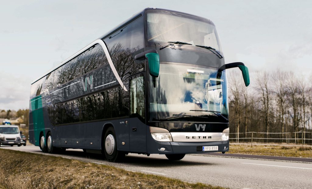 En grønn double decker buss som kjører